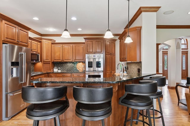 2906 Butternut Dr, Chaska, MN 55318 - kitchen with appliances with stainless steel finishes, arched walkways, crown molding, brown cabinets, and a peninsula