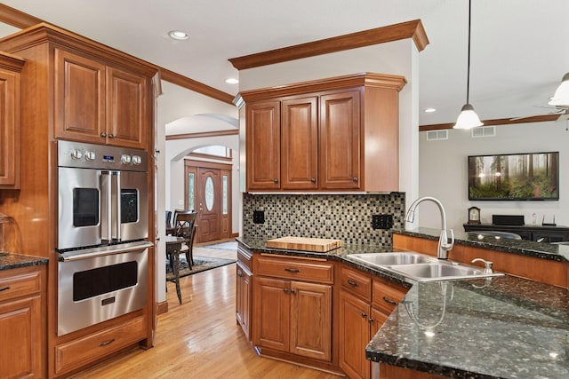 2906 Butternut Dr, Chaska, MN 55318 - kitchen with stainless steel double oven, arched walkways, crown molding, brown cabinets, and recessed lighting