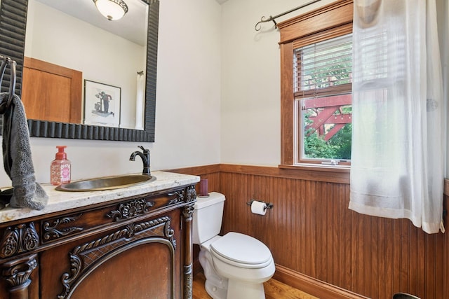 2906 Butternut Dr, Chaska, MN 55318 - half bath featuring wainscoting, healthy amount of natural light, vanity, wood finished floors, and wood walls