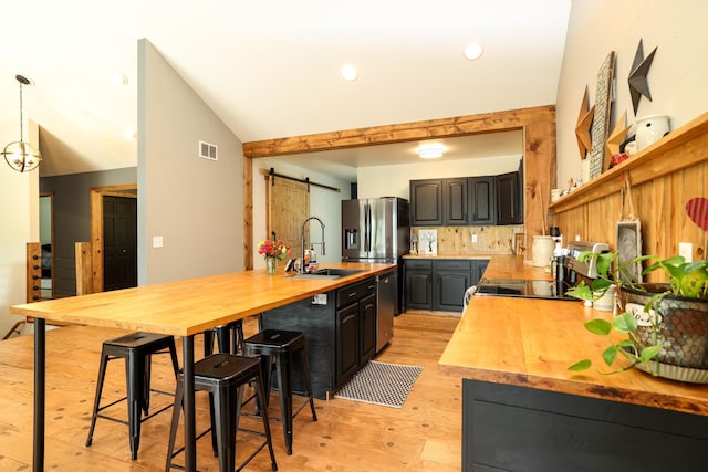 3250 Wild Turkey Ln, Red Wing, MN 55066 - kitchen with wood counters, light wood finished floors, decorative backsplash, a barn door, and vaulted ceiling