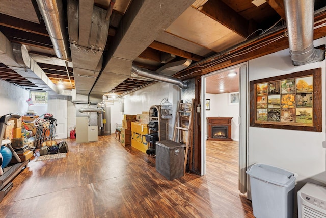 5718 13th Ave S, Minneapolis, MN 55417 - below grade area featuring wood finished floors, water heater, heating unit, and a lit fireplace