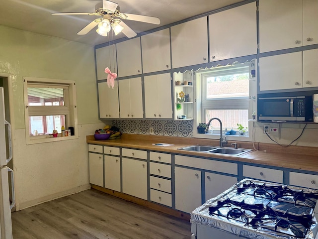 114 Thompson Ave, Rushmore, MN 56168 - kitchen featuring light wood-style flooring, white cabinets, a ceiling fan, and backsplash
