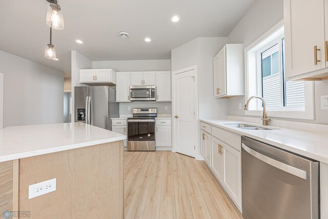 6646 68th St S, Horace, ND 58047 - kitchen featuring appliances with stainless steel finishes, light wood finished floors, decorative light fixtures, a kitchen island, and white cabinetry