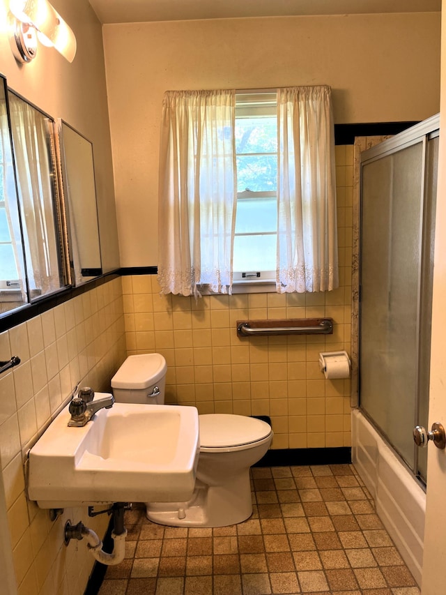 757 111th Ave NW, Coon Rapids, MN 55448 - full bath featuring healthy amount of natural light, tile walls, toilet, a wainscoted wall, and combined bath / shower with glass door