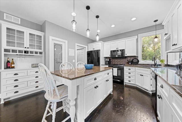 1848 141st Ln NE, Ham Lake, MN 55304 - kitchen featuring black appliances, a kitchen bar, dark stone countertops, white cabinets, and pendant lighting