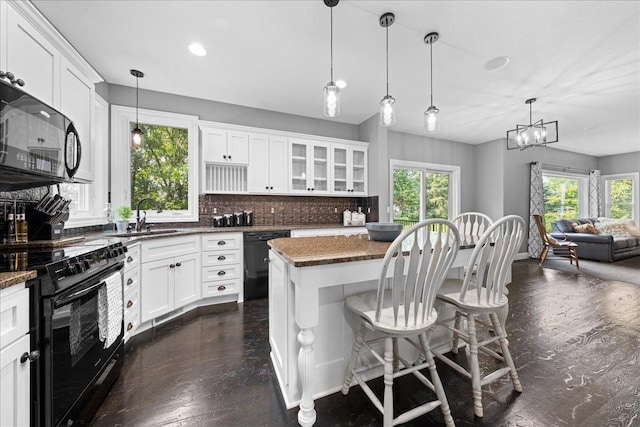 1848 141st Ln NE, Ham Lake, MN 55304 - kitchen featuring black appliances, a kitchen island, a kitchen breakfast bar, white cabinets, and dark stone counters