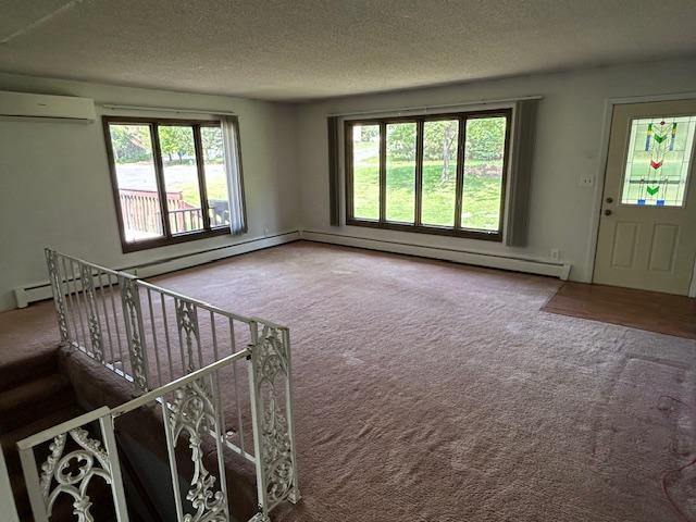 601 1st Ave, Grand Rapids, MN 55744 - unfurnished living room featuring a wall mounted AC, carpet, healthy amount of natural light, and a textured ceiling
