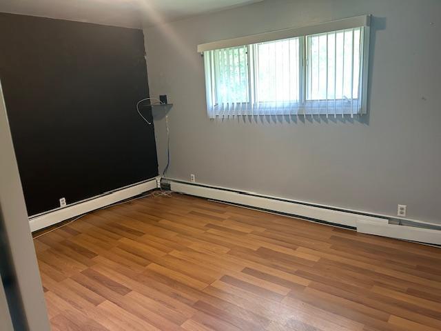 601 1st Ave, Grand Rapids, MN 55744 - spare room featuring wood finished floors and a baseboard radiator