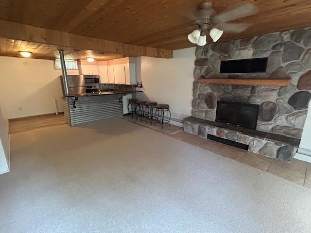 601 1st Ave, Grand Rapids, MN 55744 - carpeted living area with wood ceiling, a stone fireplace, and a ceiling fan