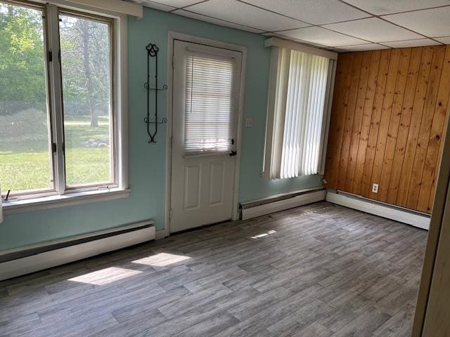 601 1st Ave, Grand Rapids, MN 55744 - foyer featuring a baseboard radiator, wood finished floors, a paneled ceiling, wooden walls, and baseboards