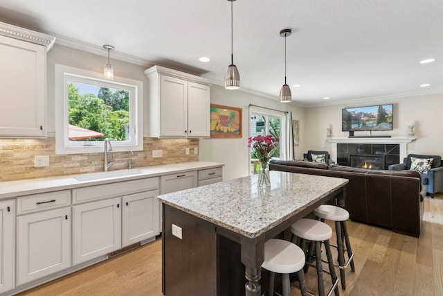 312 Barry Ave N, Wayzata, MN 55391 - kitchen with a sink, light wood finished floors, a kitchen island, plenty of natural light, and ornamental molding