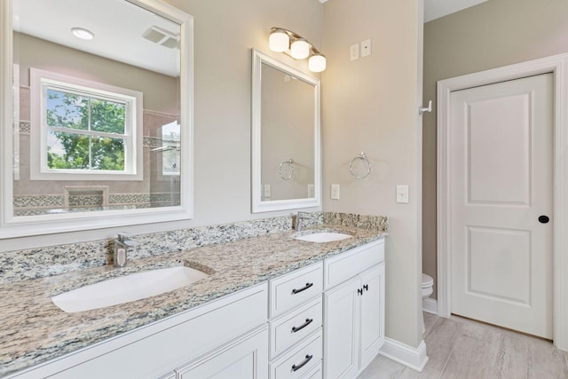 312 Barry Ave N, Wayzata, MN 55391 - bathroom with double vanity, toilet, baseboards, and tiled shower