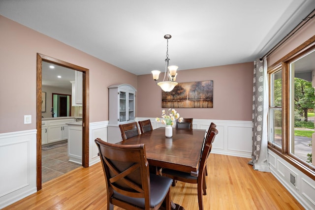 135 Glen Creek Rd NE, Fridley, MN 55432 - dining room featuring wainscoting, light wood-style floors, a decorative wall, and a chandelier
