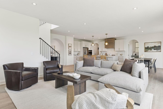 10172 Peony Ln N, Maple Grove, MN 55311 - living room featuring arched walkways, light wood-style flooring, recessed lighting, stairs, and baseboards
