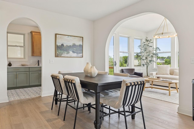 10172 Peony Ln N, Maple Grove, MN 55311 - dining room with light wood-style flooring, arched walkways, and baseboards