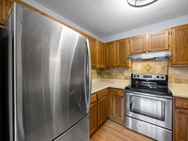 1626 Raindrop Dr, Eagan, MN 55121 - kitchen featuring appliances with stainless steel finishes, under cabinet range hood, light countertops, brown cabinetry, and a textured ceiling