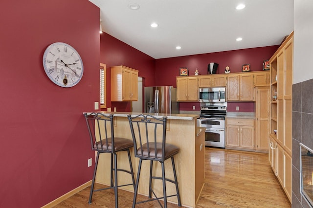 20886 Jenkins Way, Lakeville, MN 55044 - kitchen with appliances with stainless steel finishes, a peninsula, light wood-style flooring, a kitchen breakfast bar, and light brown cabinetry