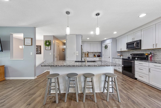 432 Garden Rd, Albert Lea, MN 56007 - kitchen featuring appliances with stainless steel finishes, decorative backsplash, a breakfast bar area, wood finished floors, and a textured ceiling