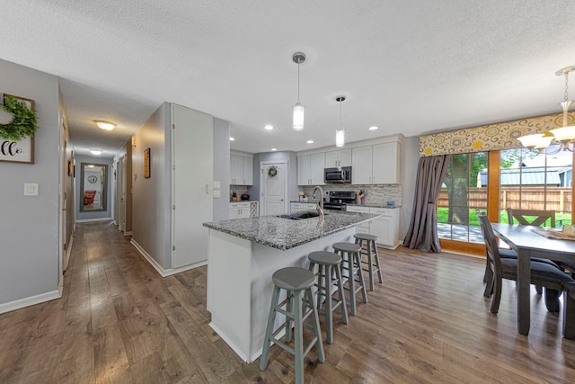 432 Garden Rd, Albert Lea, MN 56007 - kitchen with stainless steel appliances, a textured ceiling, a chandelier, a center island with sink, and dark wood-style flooring