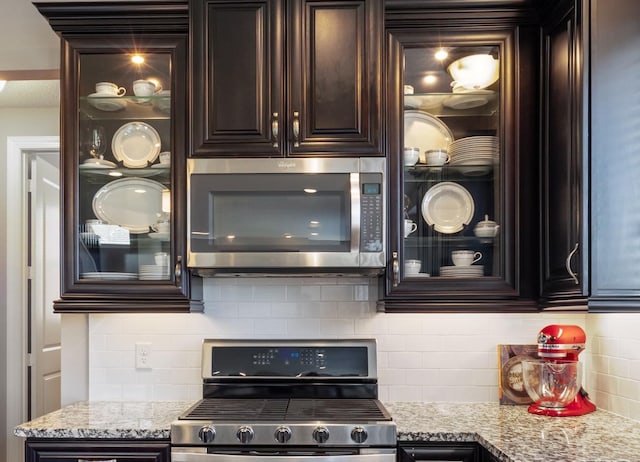 1270 Crosswinds Ct, Waconia, MN 55387 - kitchen featuring stainless steel appliances, dark brown cabinetry, backsplash, and glass insert cabinets