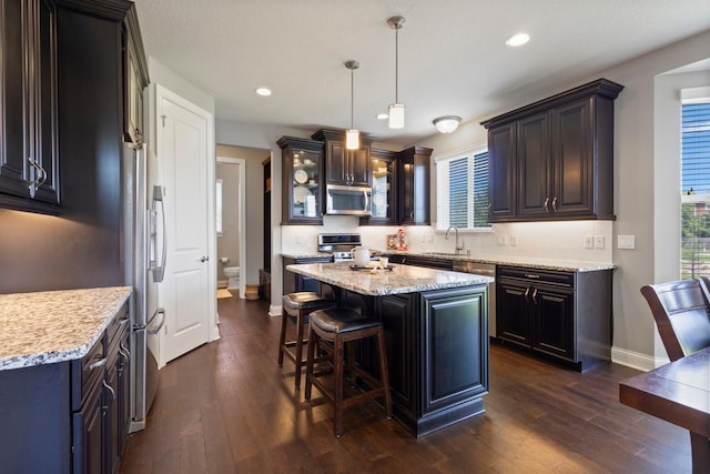 1270 Crosswinds Ct, Waconia, MN 55387 - kitchen with stainless steel appliances, a kitchen bar, baseboards, a sink, and dark wood-style floors