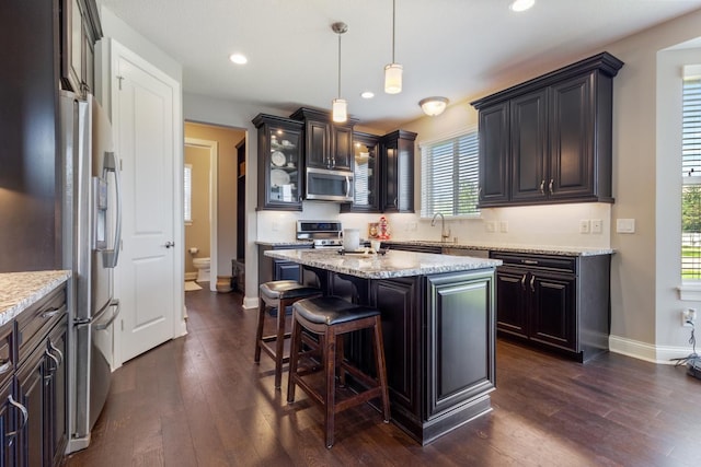 1270 Crosswinds Ct, Waconia, MN 55387 - kitchen with stainless steel appliances, dark wood-style floors, a kitchen bar, a kitchen island, and glass insert cabinets