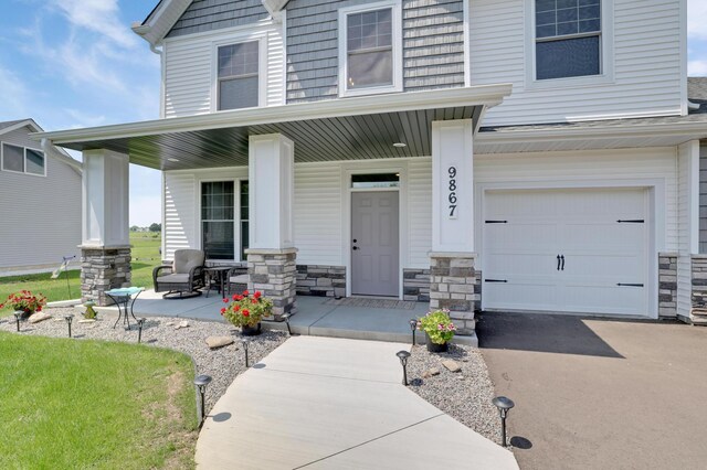 9867 Kahler Ave NE, Monticello, MN 55362 - view of front of property with covered porch, a garage, and stone siding