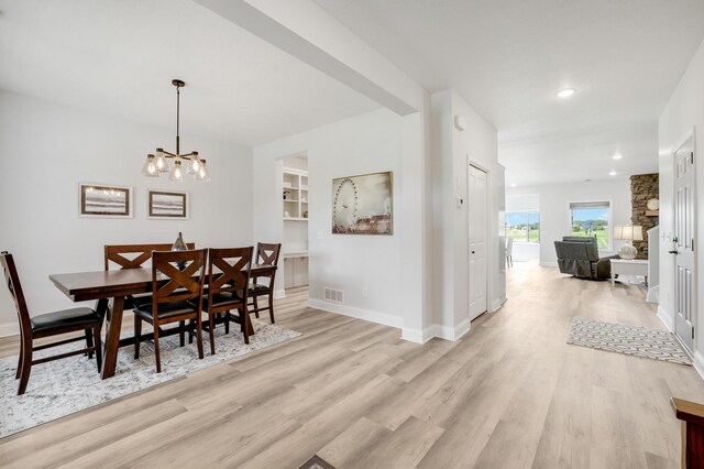 9867 Kahler Ave NE, Monticello, MN 55362 - dining space featuring light wood-style flooring, a chandelier, recessed lighting, baseboards, and built in features