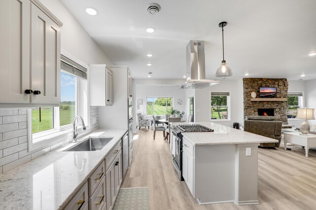 9867 Kahler Ave NE, Monticello, MN 55362 - kitchen with a sink, island exhaust hood, light wood finished floors, a fireplace, and a center island