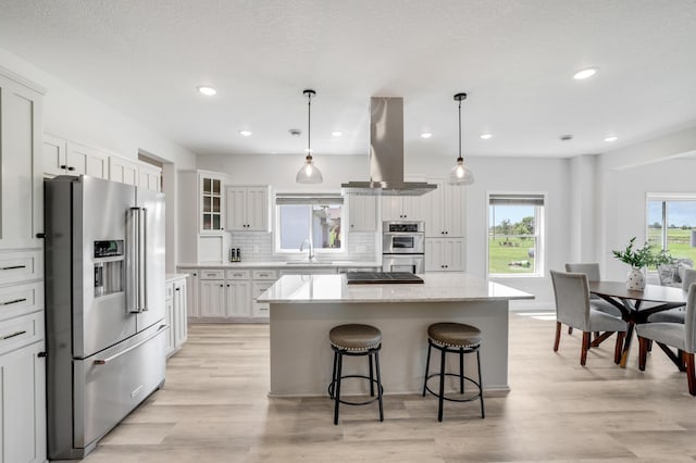 9867 Kahler Ave NE, Monticello, MN 55362 - kitchen featuring appliances with stainless steel finishes, island exhaust hood, a sink, a center island, and tasteful backsplash