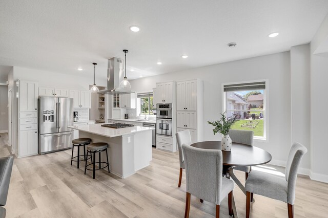 9867 Kahler Ave NE, Monticello, MN 55362 - kitchen with appliances with stainless steel finishes, a center island, white cabinets, light wood finished floors, and recessed lighting