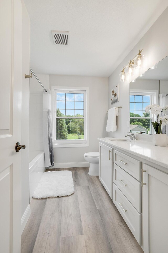 9867 Kahler Ave NE, Monticello, MN 55362 - full bathroom with vanity, wood finished floors, toilet, shower / bathtub combination, and baseboards