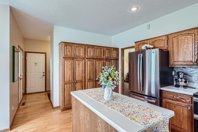 11760 88th Pl N, Maple Grove, MN 55369 - kitchen with freestanding refrigerator, light countertops, light wood-type flooring, brown cabinetry, and a textured ceiling