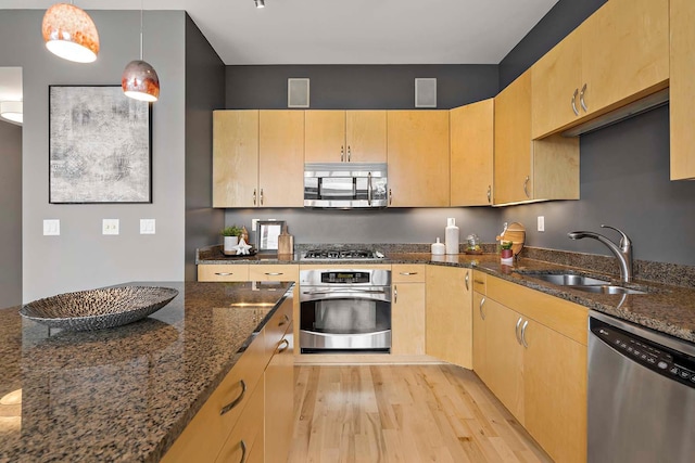 215 10th Ave S Unit 425, Minneapolis, MN 55415 - kitchen featuring stainless steel appliances, light brown cabinetry, light wood-style flooring, dark stone countertops, and hanging light fixtures