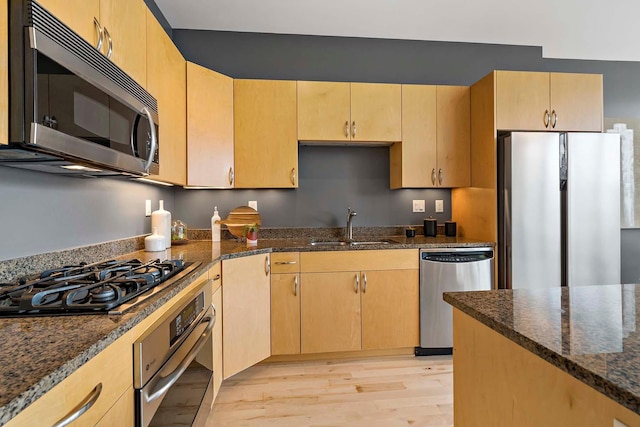 215 10th Ave S Unit 425, Minneapolis, MN 55415 - kitchen featuring appliances with stainless steel finishes, dark stone counters, light wood-style floors, and light brown cabinetry