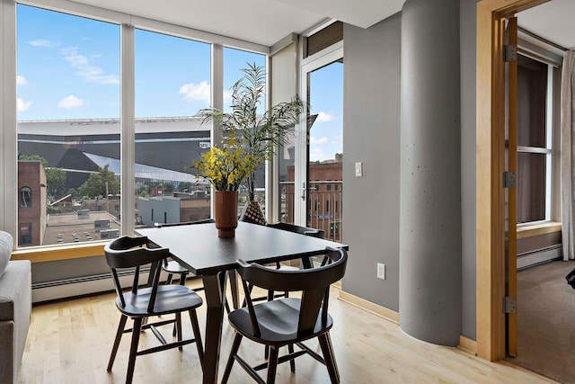 215 10th Ave S Unit 425, Minneapolis, MN 55415 - dining room featuring a baseboard radiator, light wood-style flooring, and floor to ceiling windows