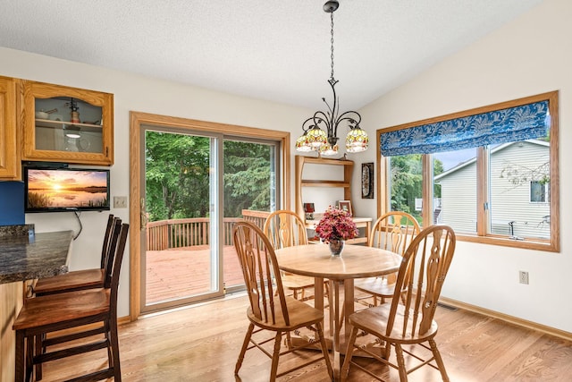 1201 Maplewood Dr, Delano, MN 55328 - dining room with light wood-type flooring, a chandelier, baseboards, lofted ceiling, and a textured ceiling