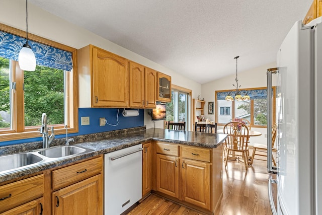 1201 Maplewood Dr, Delano, MN 55328 - kitchen with white appliances, a sink, light wood-style flooring, a peninsula, and lofted ceiling
