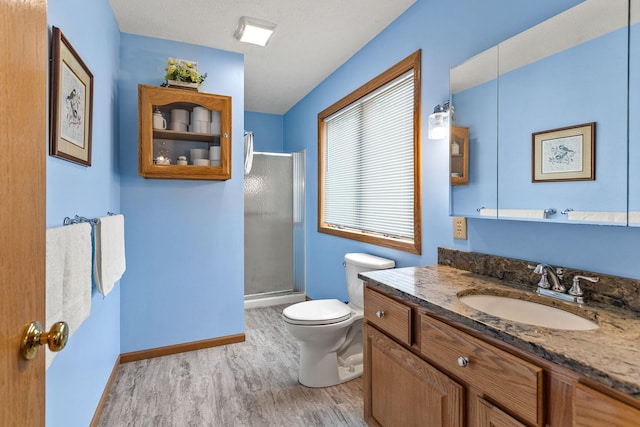 1201 Maplewood Dr, Delano, MN 55328 - bathroom featuring wood finished floors, toilet, a shower stall, vanity, and baseboards