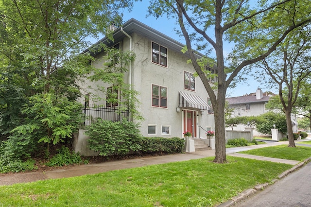 666 Ashland Ave Unit 5, Saint Paul, MN 55104 - view of front of house featuring stucco siding, a front yard, and a chimney
