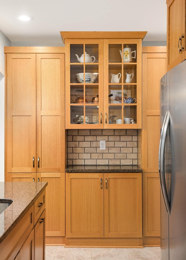 4313 Arthur St NE, Columbia Heights, MN 55421 - kitchen featuring freestanding refrigerator, dark stone counters, glass insert cabinets, and tasteful backsplash