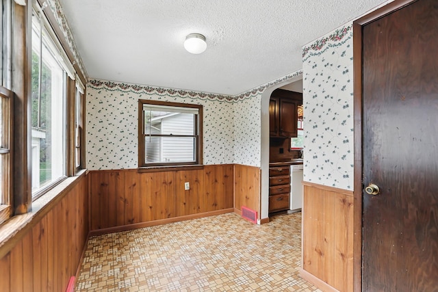 1206 2nd St W, Hastings, MN 55033 - spare room with wainscoting, a textured ceiling, healthy amount of natural light, wood walls, and wallpapered walls