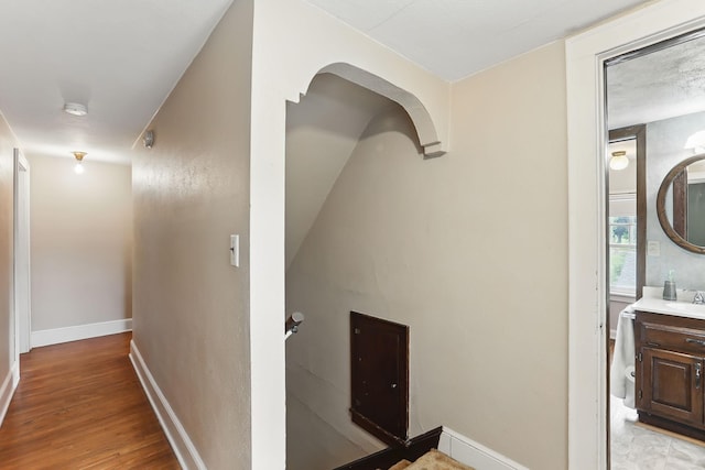 1206 2nd St W, Hastings, MN 55033 - corridor featuring a sink, baseboards, light wood-type flooring, arched walkways, and an upstairs landing