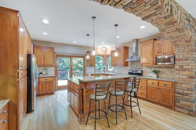 904 Ridgecrest Dr, Carver, MN 55315 - kitchen featuring wall chimney range hood, stainless steel appliances, light wood-type flooring, brown cabinetry, and recessed lighting