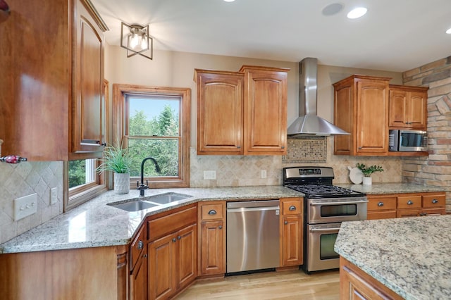 904 Ridgecrest Dr, Carver, MN 55315 - kitchen featuring appliances with stainless steel finishes, wall chimney range hood, light wood-style flooring, light stone countertops, and backsplash