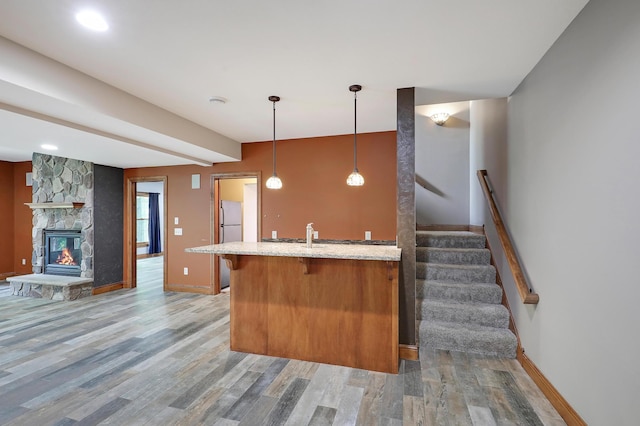 904 Ridgecrest Dr, Carver, MN 55315 - kitchen with light wood-style flooring, light stone countertops, a kitchen bar, hanging light fixtures, and freestanding refrigerator