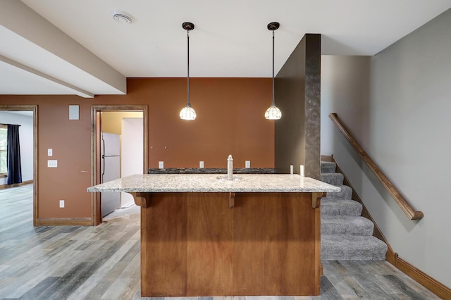 904 Ridgecrest Dr, Carver, MN 55315 - kitchen featuring freestanding refrigerator, a breakfast bar area, light wood finished floors, light stone countertops, and decorative light fixtures