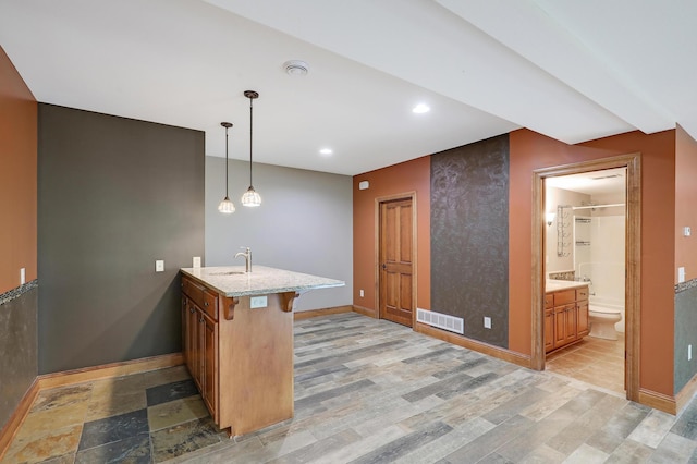 904 Ridgecrest Dr, Carver, MN 55315 - kitchen with a peninsula, light stone counters, recessed lighting, a kitchen bar, and brown cabinetry