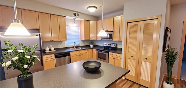 1805 3rd Ave S Unit 102, Minneapolis, MN 55404 - kitchen with stainless steel appliances, dark countertops, light brown cabinets, and pendant lighting