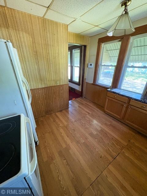 1539 Iglehart Ave, Saint Paul, MN 55104 - unfurnished dining area with wooden walls, a drop ceiling, light wood finished floors, and a wainscoted wall